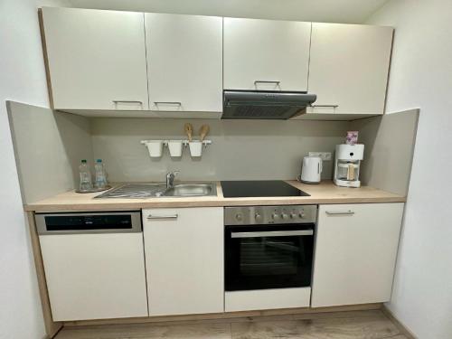 a small kitchen with white cabinets and a sink at Ferienwohnungen GoJa in Bad Königshofen im Grabfeld