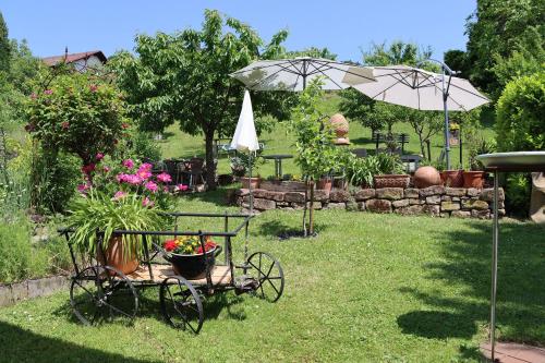 un jardín con un carro con flores y una sombrilla en Fewo Odenwald - Marie, en Breuberg