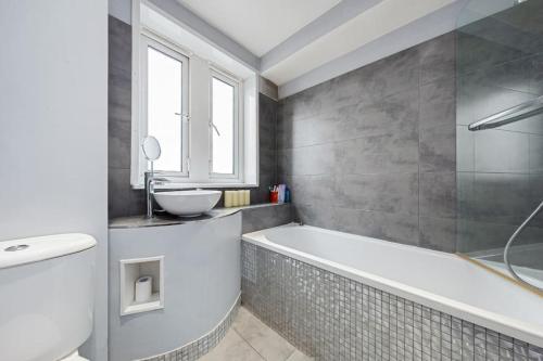 a bathroom with a bath tub and a sink at Top Floor 1 Bedroom Apartment with views over London in London