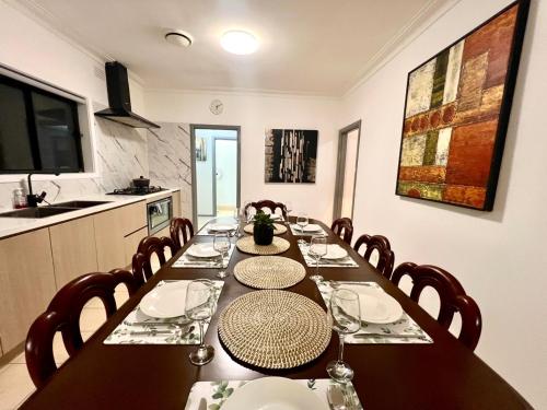 a dining room with a long table in a kitchen at Cosy 5BR Home 10 minutes away from Melbourne Airport in Albion