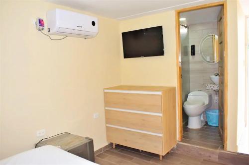 a bathroom with a toilet and a tv on the wall at Cabañas covemar in Coveñas