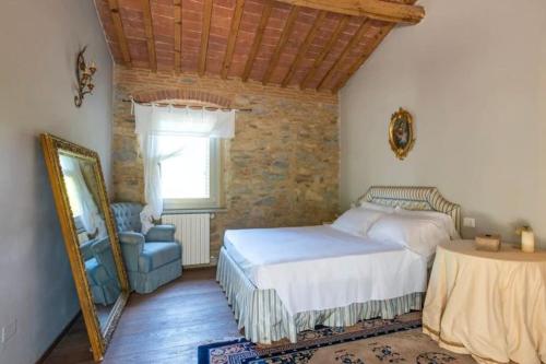1 dormitorio con cama, espejo y silla en Villa mulino del 500, en Carmignano