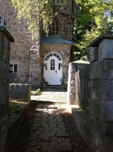 a stone building with a white door and a fence at Villa Breitenberg in Breitenberg