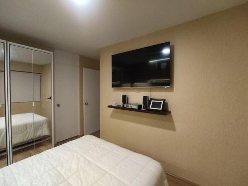 a bedroom with a bed and a flat screen tv at Acogedor Departamento de estreno frente al mar in Lima