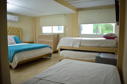 1 dormitorio con 2 camas y 2 ventanas en Cabañas covemar, en Coveñas