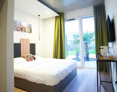 een slaapkamer met een bed en een groot raam bij Arrow Hôtel in Hégenheim