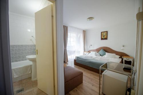 a hotel room with a bed and a bathroom at Hotel Barbizon in Nyíregyháza