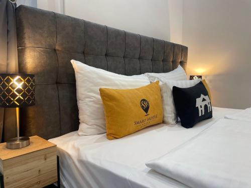 a bed with white and black pillows on it at Smart Hotel Budapest in Budapest