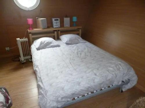 - une chambre dotée d'un grand lit avec des draps blancs et une fenêtre dans l'établissement House boat AJA, à Vigneux-sur-Seine