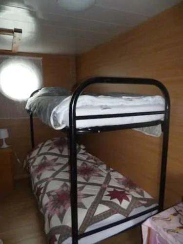 deux lits superposés dans une chambre avec fenêtre dans l'établissement House boat AJA, à Vigneux-sur-Seine