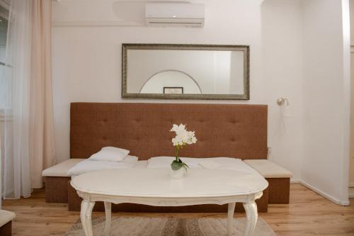 a white table with a vase of flowers on it at Hotel Barbizon in Nyíregyháza