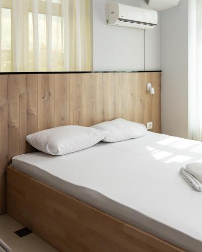 a bed with a wooden headboard and white pillows at Hotel United PR in Prishtinë