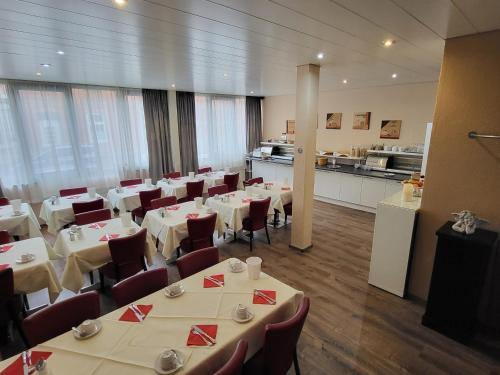 a restaurant with white tables and chairs and a kitchen at Concorde Hotel Ascot in Düsseldorf