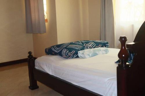 een slaapkamer met een bed met een wit en blauw kussen bij Lovely 5-Bed House in Ndejje Kampala in Kampala