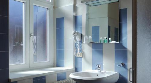 a blue and white bathroom with a sink and a window at Hotel Croda Rossa in Carbonin