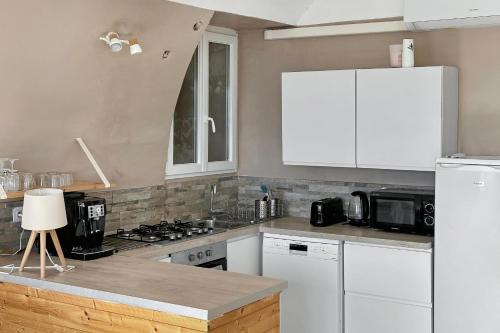 a kitchen with white cabinets and a white refrigerator at Les Terrasses du Château I Electio in Lauris
