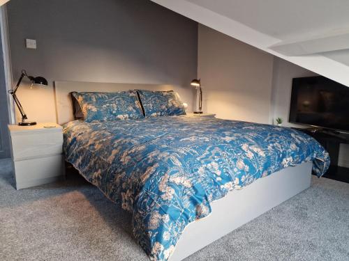 a bedroom with a bed with a blue comforter at The Penthouse NY Loft Apartment in Barmouth