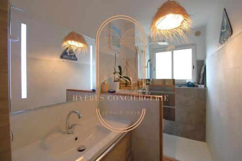 ein Badezimmer mit einem Waschbecken und einem großen Spiegel in der Unterkunft Hyères Ville-Charmant T3 RDJ By HC in Hyères