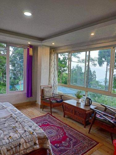 1 dormitorio con cama, mesa y ventanas en PUBELA VILLA HOMESTAY, en Darjeeling