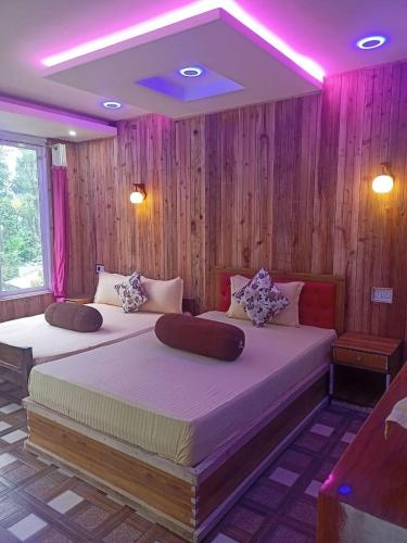 2 camas en una habitación con iluminación rosa en PUBELA VILLA HOMESTAY, en Darjeeling