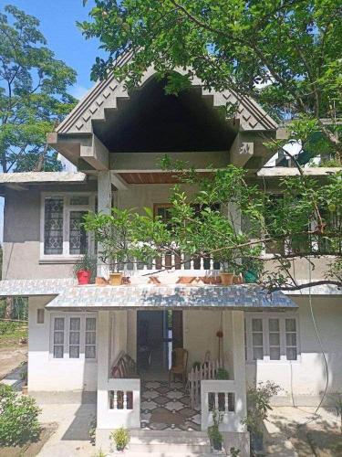 een groot wit huis met een veranda en een patio bij PUBELA VILLA HOMESTAY in Darjeeling