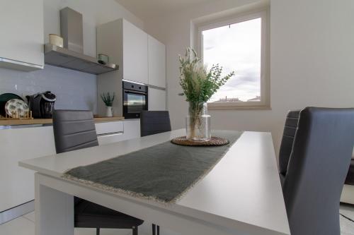 a kitchen with a table with a vase of flowers on it at Sky Suite Green Pomezia in Pomezia