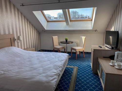 a hotel room with a bed and a tv and a table at All-in rooms in Vilnius