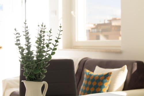 a vase with a plant on a table next to a couch at Sky Suite Blue Pomezia in Pomezia