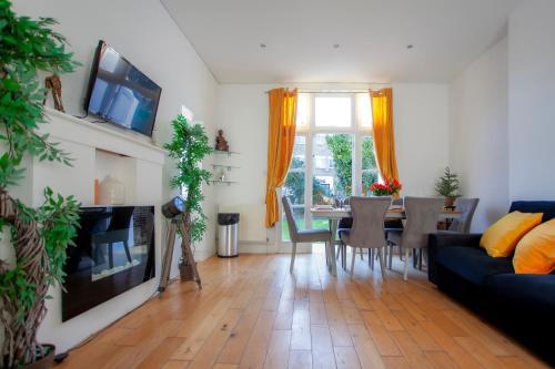 a living room with a couch and a table with chairs at Templar large garden flat in London