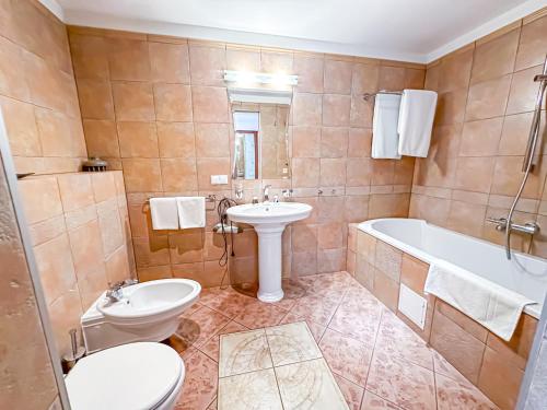 a bathroom with a toilet and a sink and a tub at All-in rooms in Vilnius