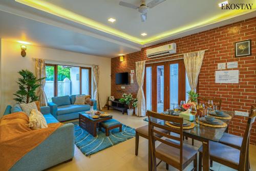 - un salon avec un canapé bleu et un mur en briques dans l'établissement EKO STAY - Solace Villa I Charming Villa close to Candolim Beach, à Marmagao