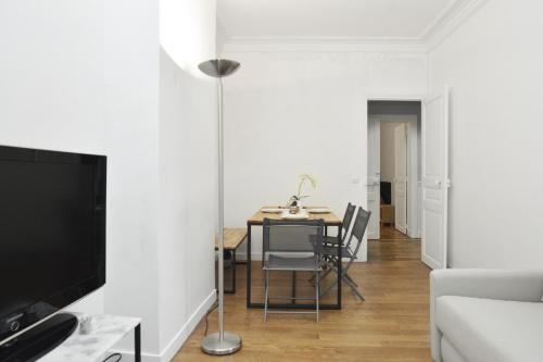 un salon avec une table à manger et une télévision dans l'établissement -Votre nid familial parisien - Batignolles, à Paris