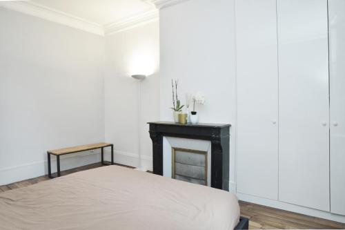 une chambre avec un lit et une cheminée dans l'établissement -Votre nid familial parisien - Batignolles, à Paris