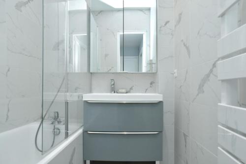 une salle de bain blanche avec un lavabo et un miroir dans l'établissement -Votre nid familial parisien - Batignolles, à Paris