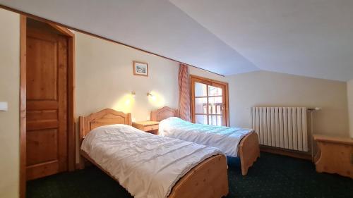 une chambre d'hôtel avec deux lits et une fenêtre dans l'établissement Alpina Lodge - 12 - Appart spacieux - 8 pers, à Les Deux Alpes