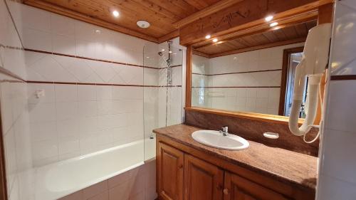 a bathroom with a sink and a mirror and a tub at Alpina Lodge - 12 - Appart spacieux - 8 pers in Les Deux Alpes