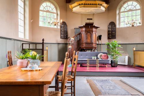 a dining room with a table and a couch at Pieter Stuyvesantkerk Peperga-Friesland in Peperga