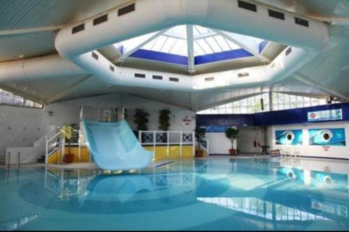 een zwembad met een blauwe glijbaan in een gebouw bij Rockley Park- Turlin Valley 36 in Lytchett Minster