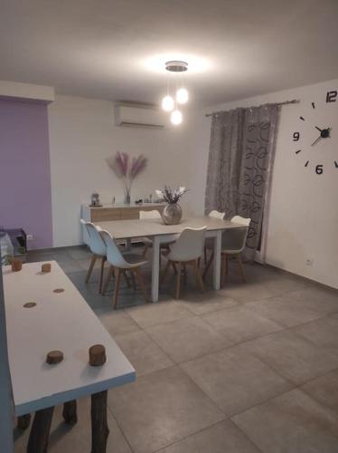 une salle à manger avec une table et une horloge au mur dans l'établissement Villa au calme / Clim / Barbecue / Parking /Plage, à Fréjus