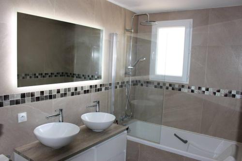 La salle de bains est pourvue de 2 lavabos, d'une douche et d'un miroir. dans l'établissement Villa au calme / Clim / Barbecue / Parking /Plage, à Fréjus