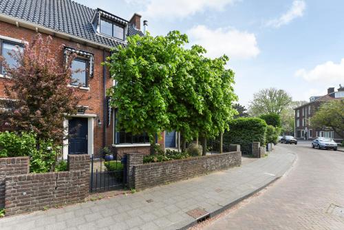 a brick house with a tree on a street at Luxury home in quiet neighbourhood near beach in The Hague