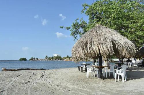 een tafel en stoelen op een strand met een rieten parasol bij Cabañas covemar in Coveñas