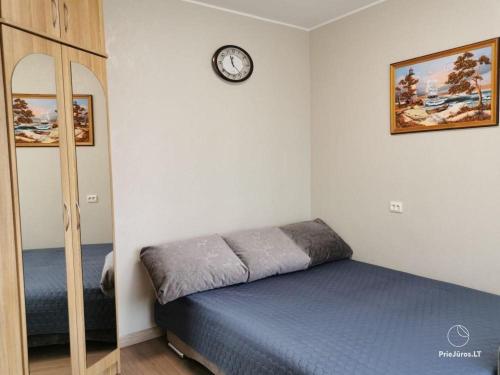 a bedroom with a bed and a clock on the wall at Vasario 16-osios 27 Kambarių nuoma in Palanga