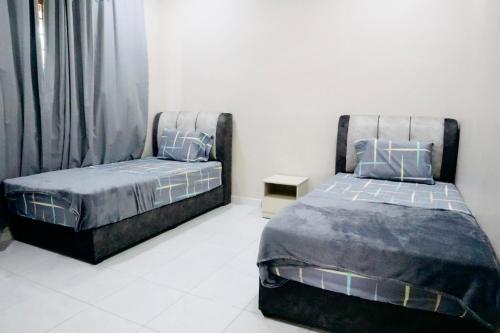 two beds sitting next to each other in a bedroom at MH Homestay No3 for 6ppl at Alor Setar in Alor Setar