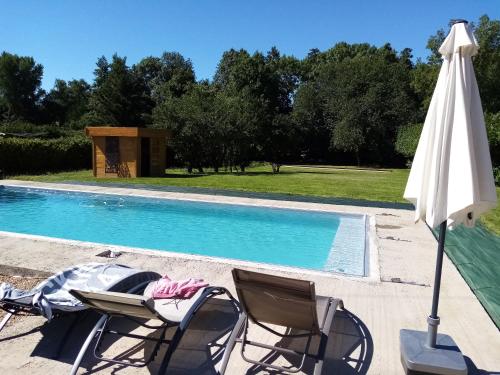 un parasol et deux chaises à côté de la piscine dans l'établissement Maison de vacances avec piscine, à Chânes