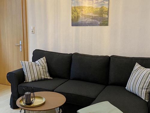 a living room with a black couch and a table at Ferienwohnung Fuldaufer in Melsungen