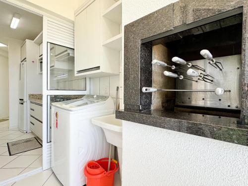 biała kuchnia ze zlewem i pralką w obiekcie Resid. Clube Mar Grosso - Laguna w mieście Laguna