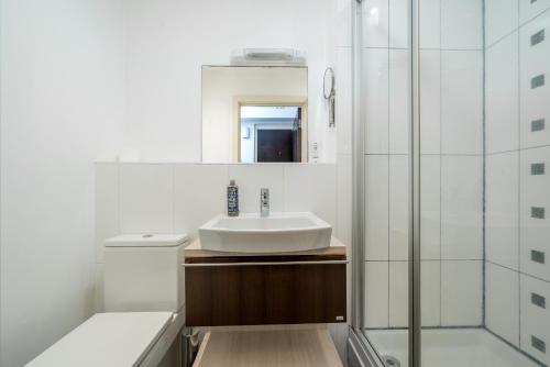 a white bathroom with a sink and a shower at Riverside 1 Bed Flat near Hampton Court Palace in East Molesey