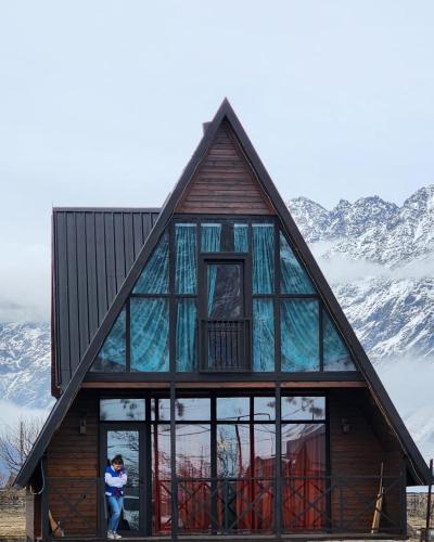 a house with glass windows and a person standing in the doorway at Deka Achkhoti in Stepantsminda