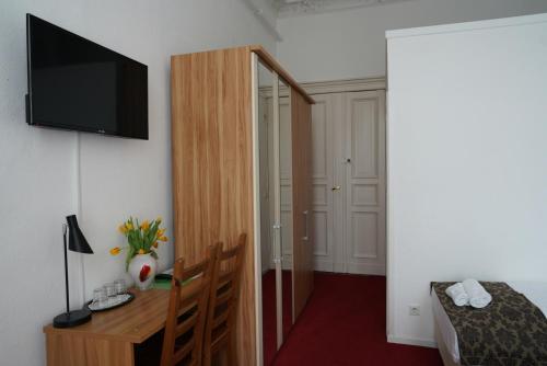 a room with a bed and a desk with a television at City Pension Berlin in Berlin